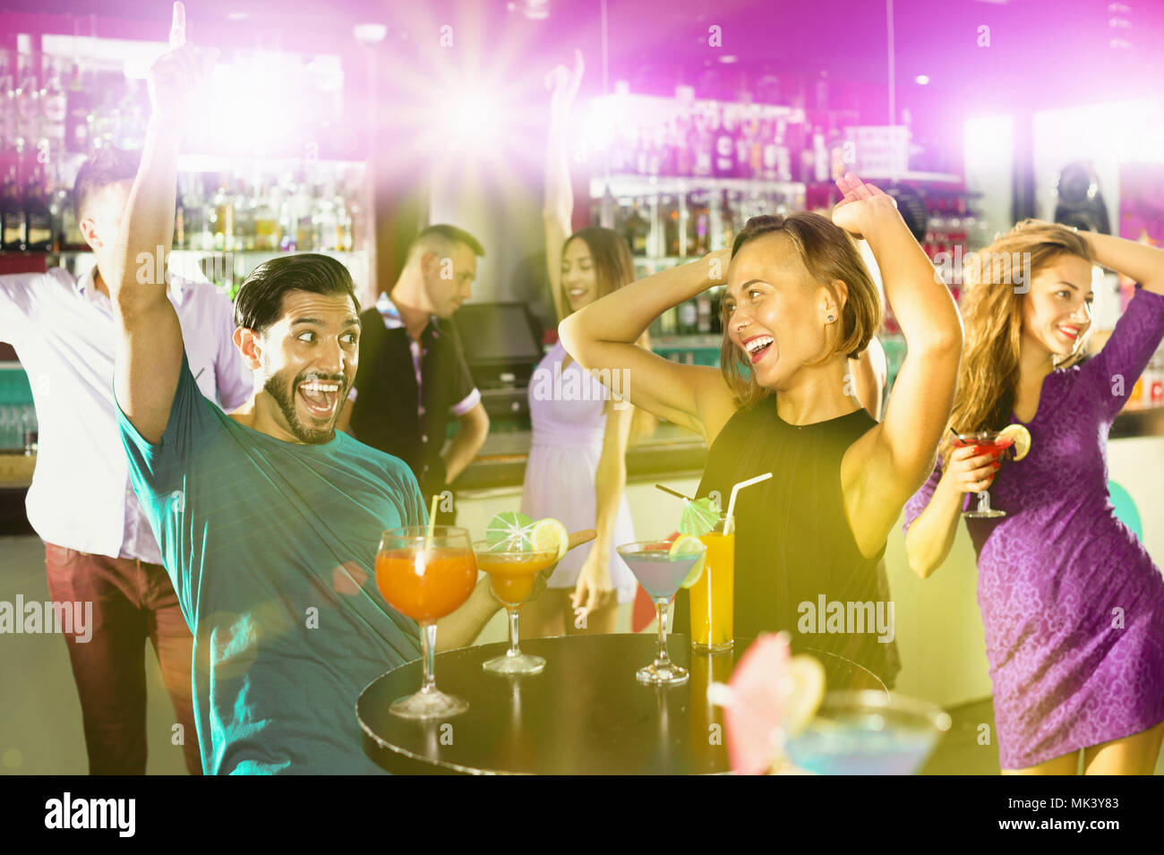 Felice allegro uomo positivo con giovani donne stanno godendo il partito in bar. Foto Stock