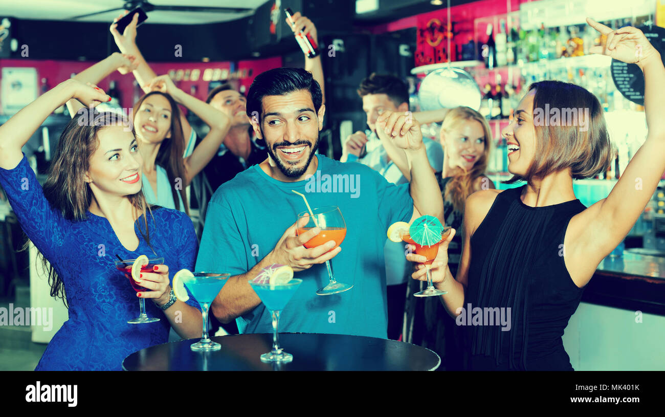 Uomo con due donne stanno bevendo un cocktail sulla parte aziendale Foto Stock