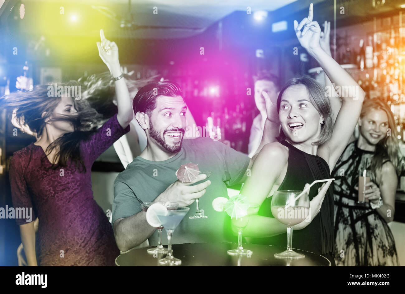 Uomo sorridente con giovani donne stanno godendo il partito in bar. Foto Stock