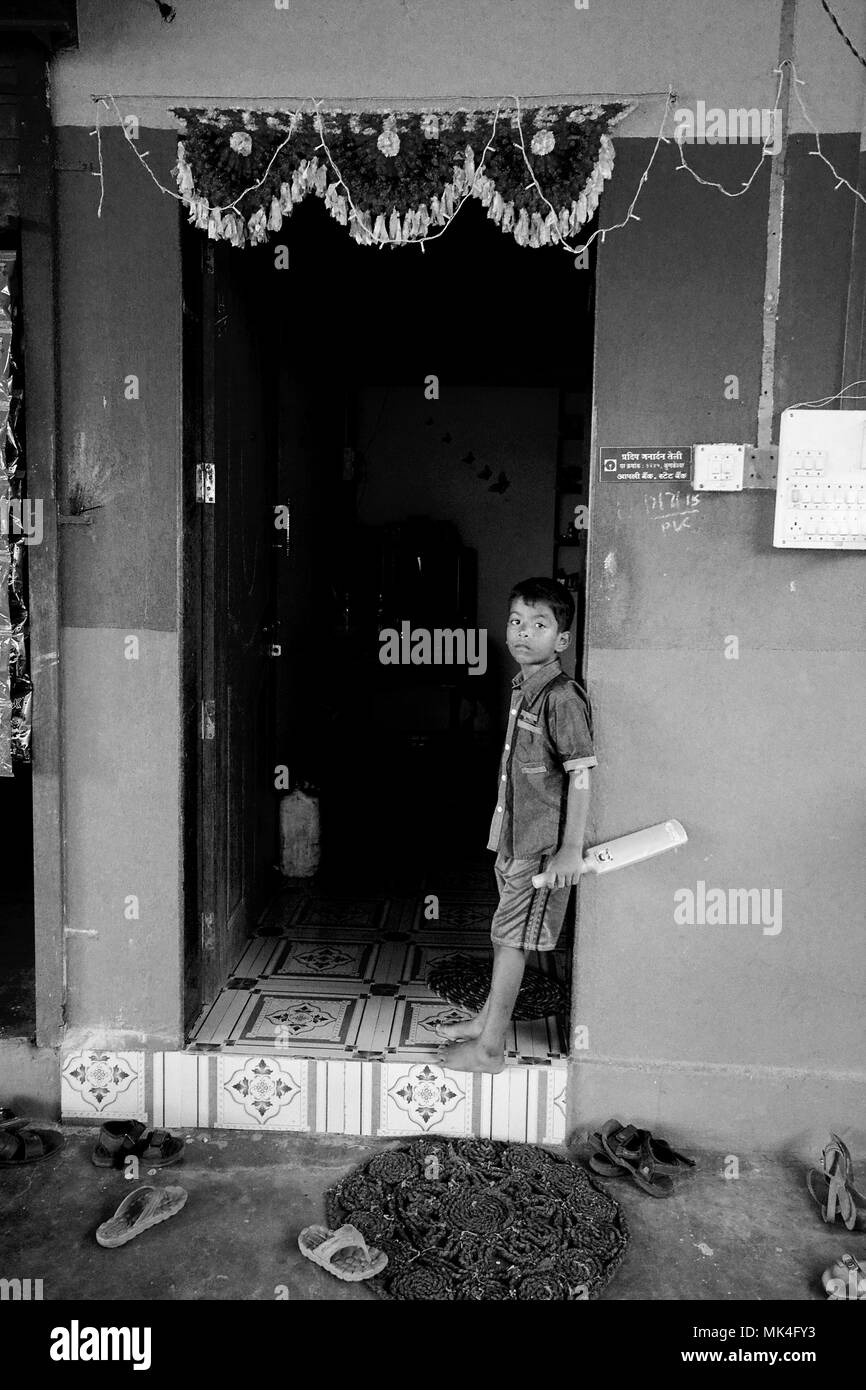 Un ragazzo si è levato in piedi nel vano della porta con la sua famiglia a casa di un cafe in India rurale Foto Stock