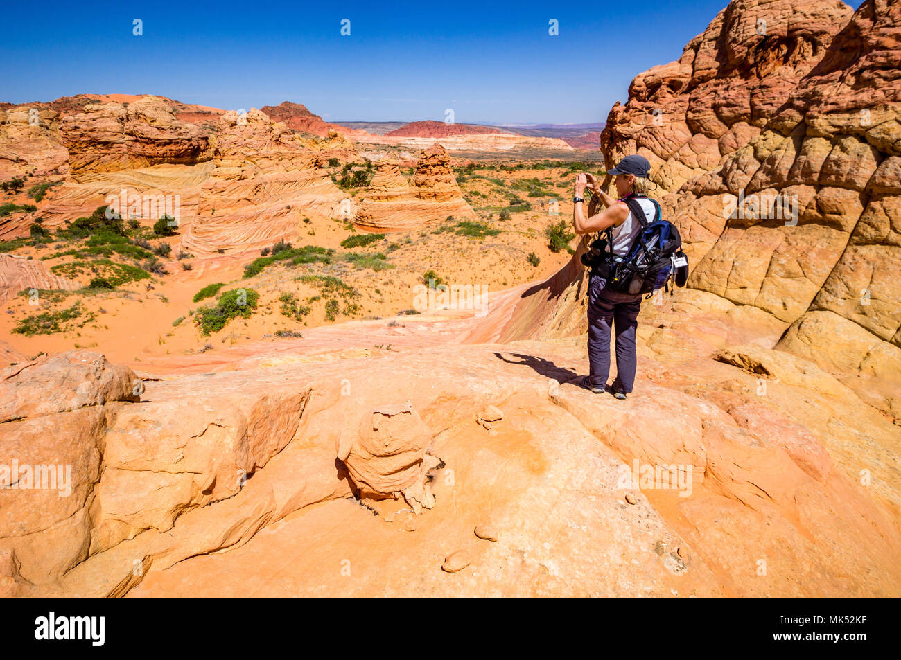 Fotografo femmina con pack fotografare colorate formazioni di pietra arenaria, Sud Coyote Buttes area, Vermiglio scogliere monumento nazionale, Arizona Foto Stock