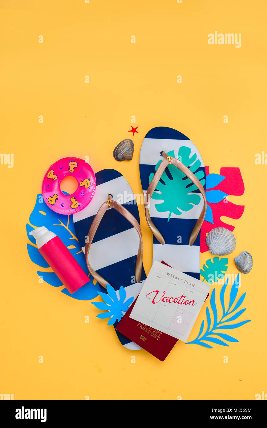 La vacanza estiva laici piatta con spiaggia accessori, flip-flop, protezione solare, passaporto, conchiglie, foglie tropicali su sfondo giallo. Travel Essentials dal di sopra con copia spazio. Moderna tavolozza colorata. Foto Stock