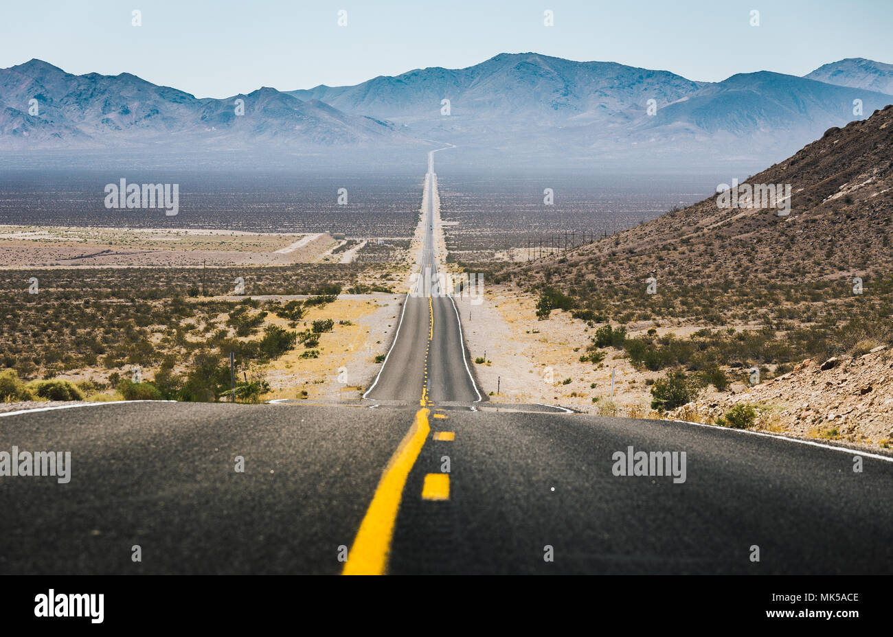 Classic vista panorama di un interminabile dritta strada che corre attraverso il paesaggio arido del sud-ovest americano Foto Stock