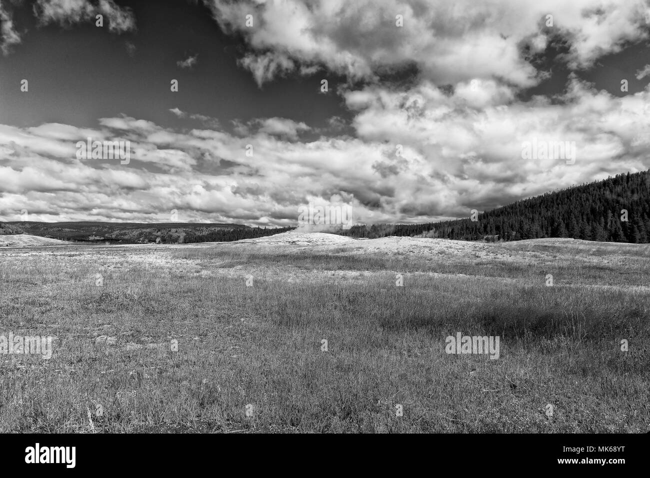 Svuotare il campo di erba con le colline di lato sotto un cielo nuvoloso, in bianco e nero. Foto Stock