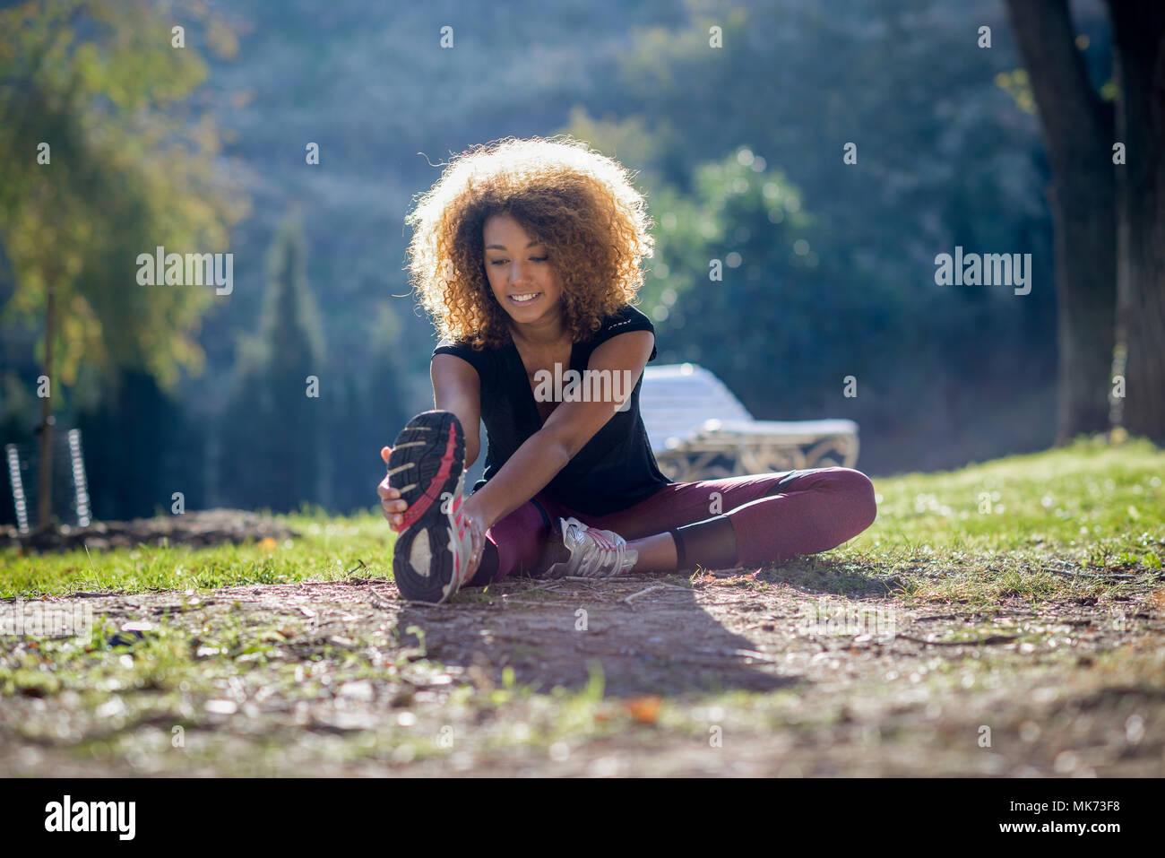 Giovane nero fitness runner donna gambe stretching dopo la corsa Foto Stock