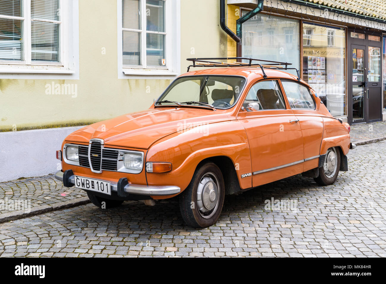 Simrishamn, Svezia - 27 Aprile 2018: documentario di viaggio della vita quotidiana e l'ambiente. Vintage orange SAAB 96 V4 dal 1974 con il portabagagli per tetto. Qui su Foto Stock