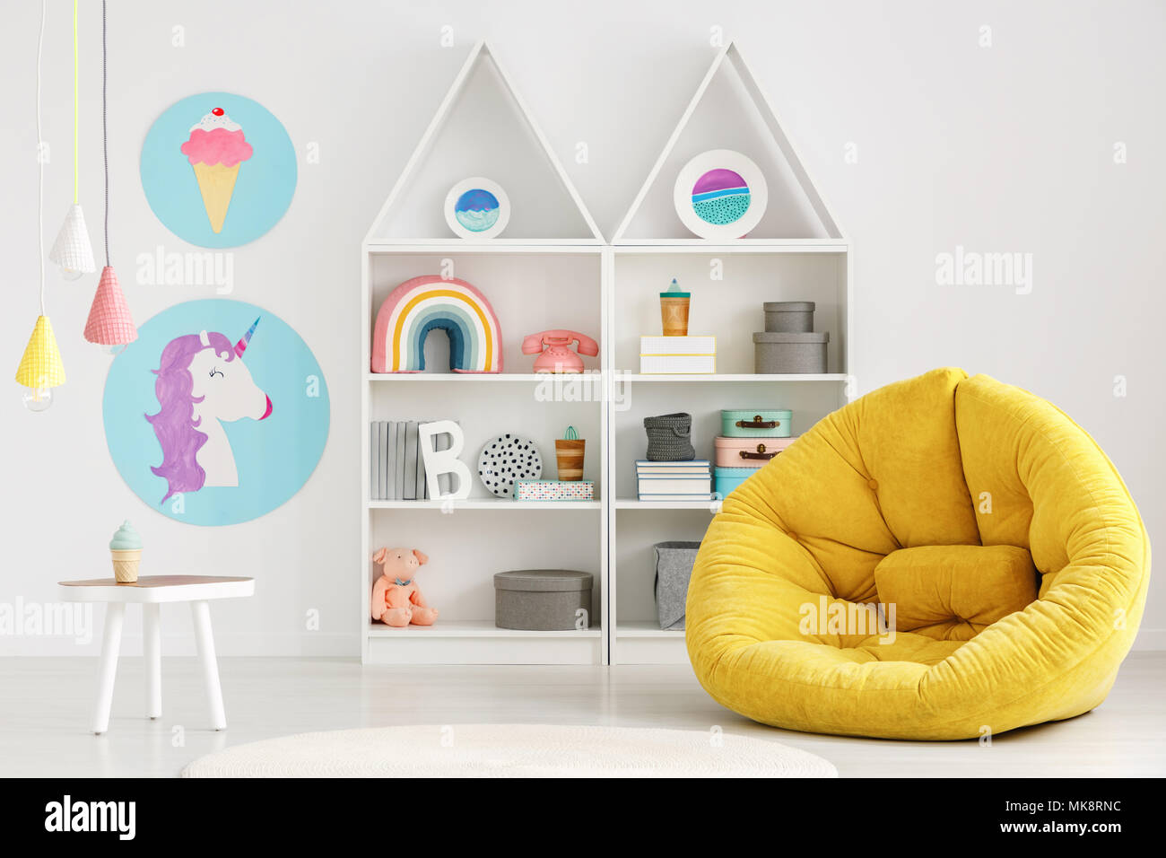 Giallo pouf in colorate scandi kid's room interior con poster e sopra le lampade tavolo bianco Foto Stock