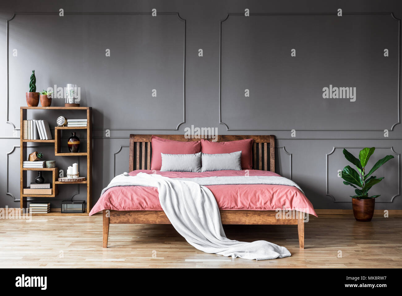 Copertura luminosa su una lettiera rosa del letto in legno nella camera da  letto grigio interno con impianto Foto stock - Alamy