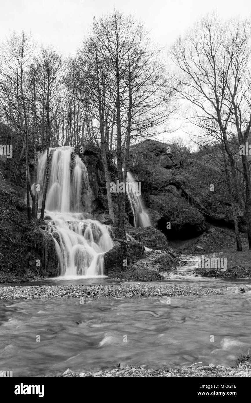 Bella cascata serbo tempo di esposizione lungo la fotografia, moto ad acqua in bianco e nero. Immagine invernale con il fiume di fronte Foto Stock