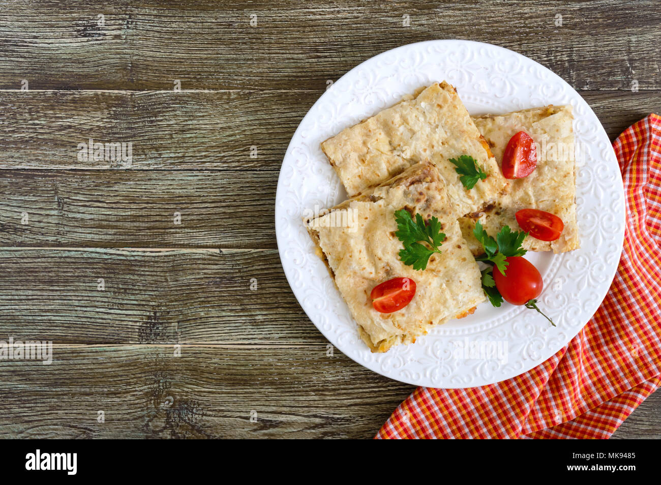 Grafico a torta, casseruola pita con funghi, ricotta e formaggio su una piastra bianca su uno sfondo di legno. Layer Cake. Vista superiore Foto Stock