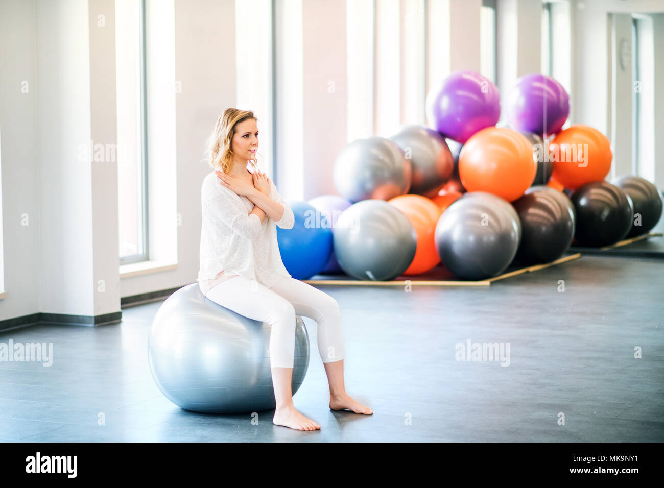 Giovane donna facendo esercizio con una fitball in una palestra. Foto Stock