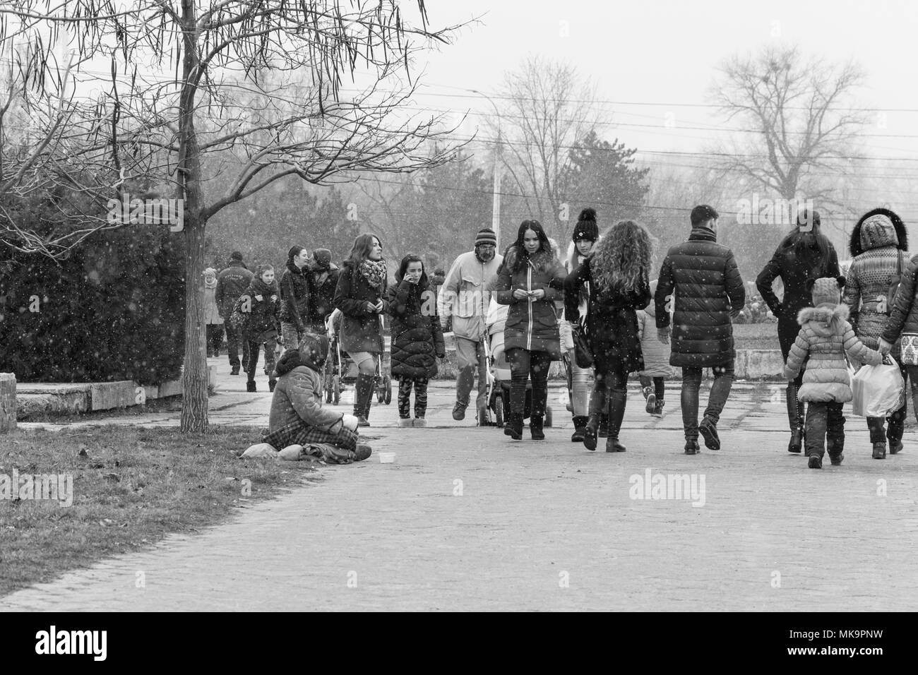 Un gruppo di persone a piedi attraverso un parco invernale, un reportage foto in bianco e nero. Foto Stock