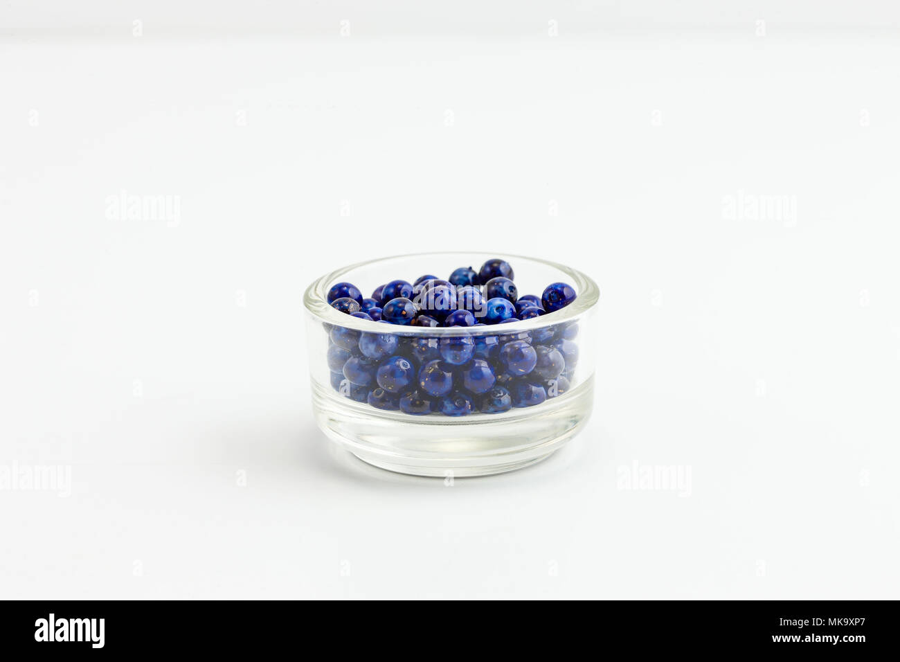 Rotondo blu con oro flecks gioielli di perline in un piccolo recipiente di vetro su bianco Foto Stock