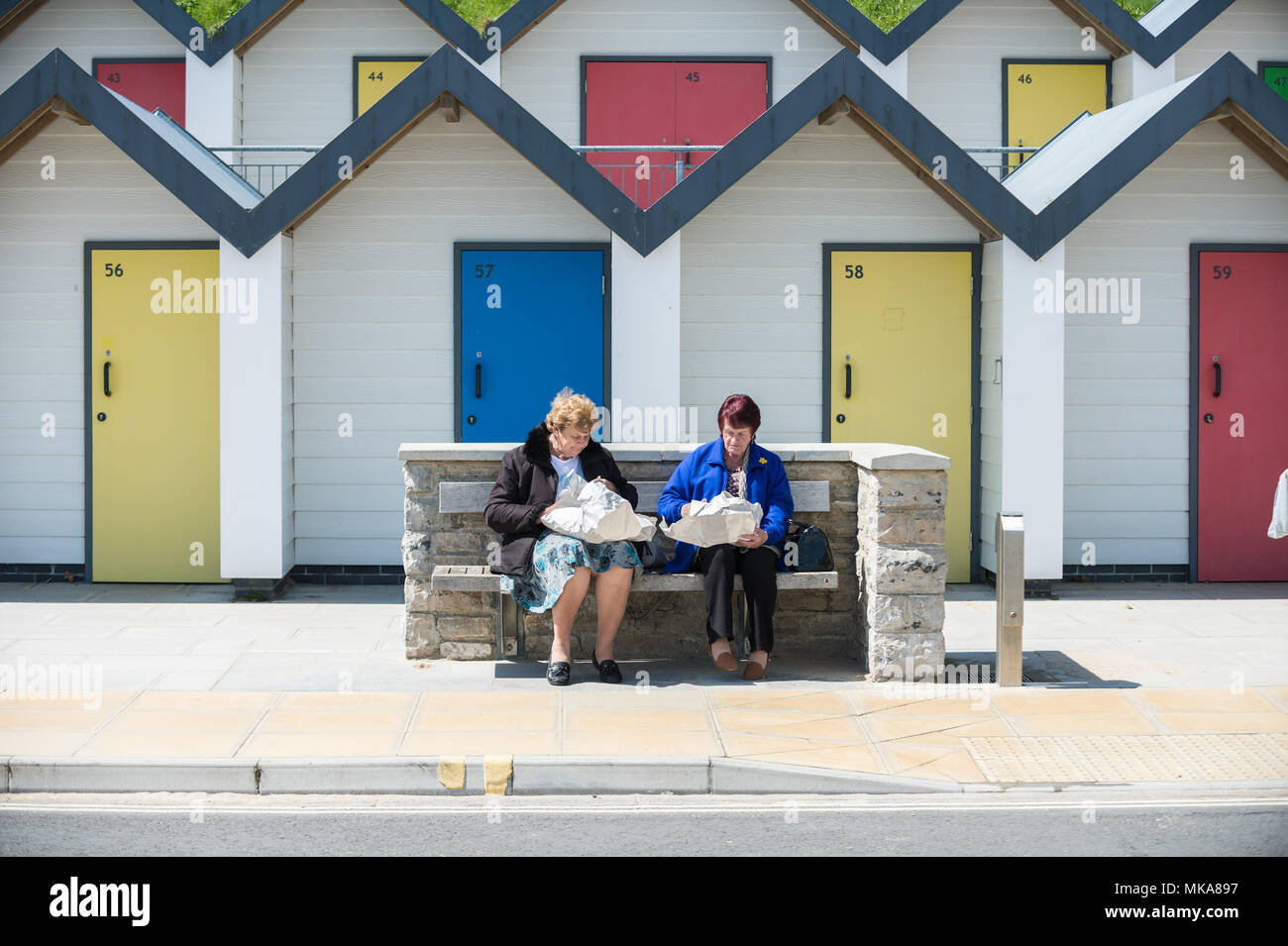 Pittoresca spiaggia di capanne stare vicino alla riva in un caldo pomeriggio assolato nella città costiera di Swanage, Dorset, Regno Unito. Foto Stock