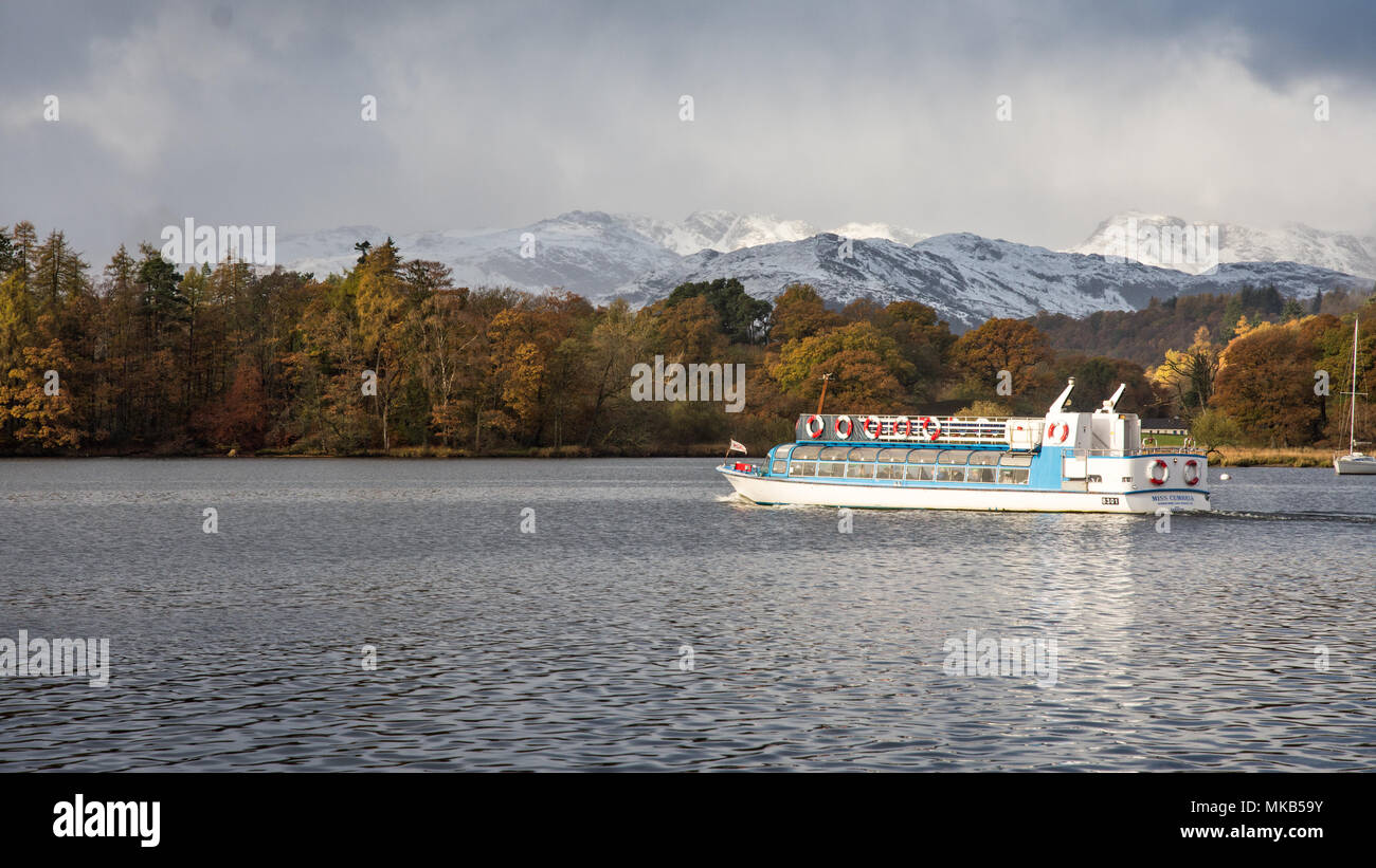 Un passeggero fery attraversa il lago Windermere dal molo Ableside, passato il Bosco in autunno le montagne innevate di Langdale, in Inghilterra del Lake District Na Foto Stock