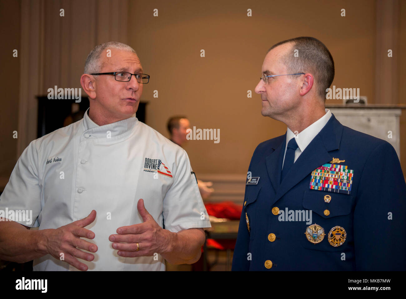 Vice Comandante della Guardia Costiera Charles Michel parla di celebrity chef Robert Irvine, durante un uso annuale omaggio ai militari dello chef che la cena in Arlington, Virginia, martedì, nov. 14, 2017. La cena è progettato per mostrare i talenti culinari di oggi gli chef di militari e le conquiste dei partecipanti. Coast Guard foto di Sottufficiali di seconda classe Loumania Stewart Foto Stock