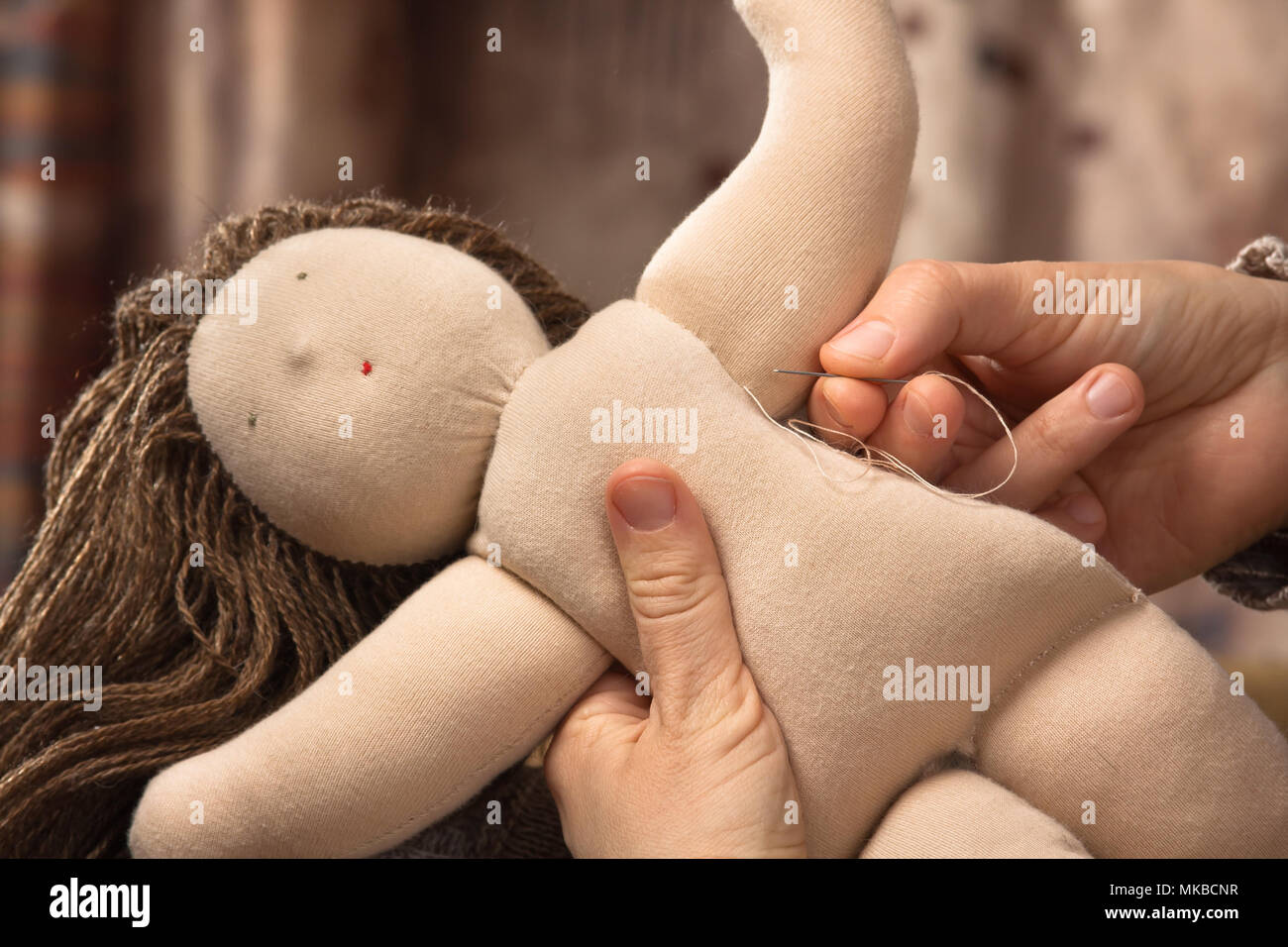 La mano della donna la cucitura di una bambola Waldorf Foto Stock