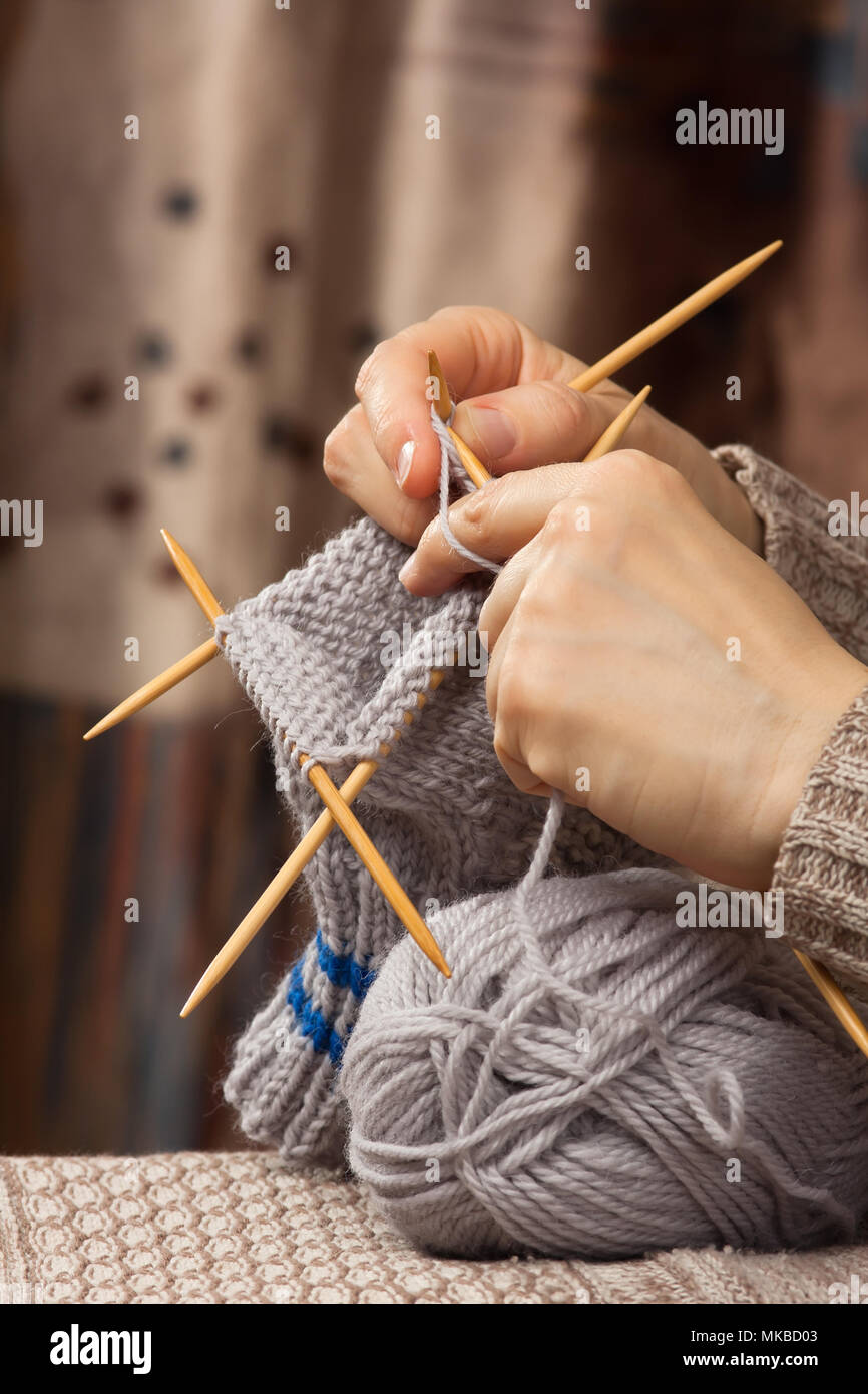 Le mani della donna tessitura di una calza con aghi di bambù Foto Stock