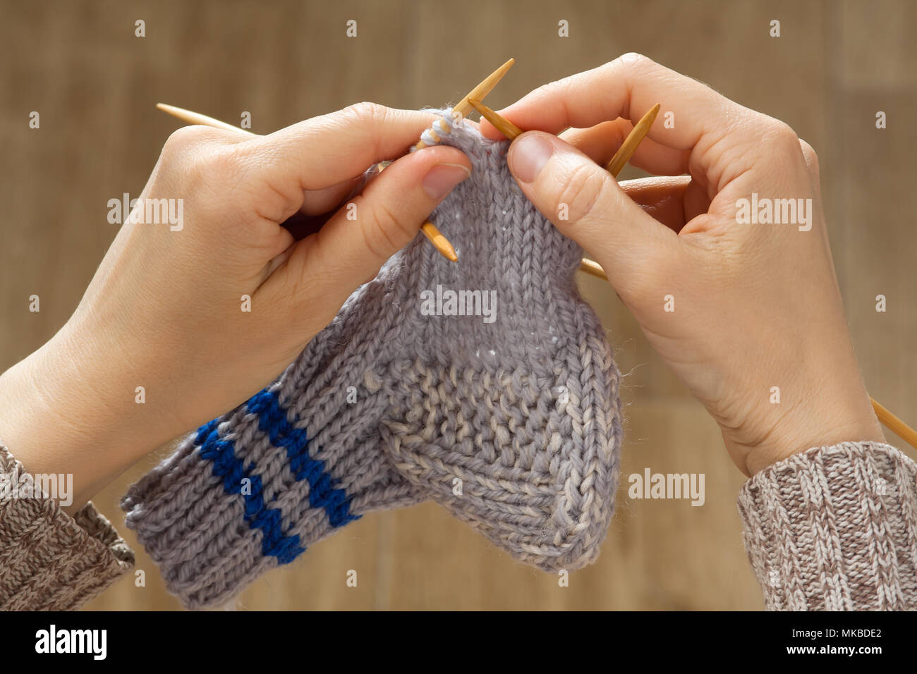 Le mani della donna tessitura di una calza con aghi di calzetteria Foto Stock