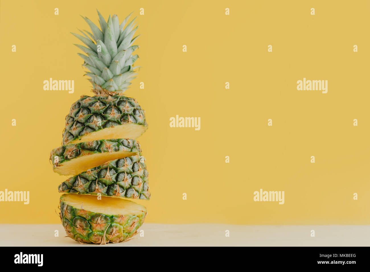 Concetto di bright succo ananas tagliato in pezzi e composto contro uno sfondo giallo. Foto Stock