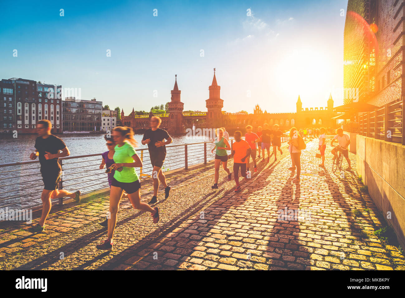 Gruppo di maschi e femmine giovani runner fuori per fare jogging in golden luce della sera al tramonto in estate con retro vintage effetto di filtro Foto Stock