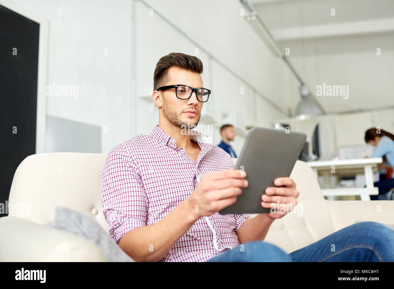 Uomo in bicchieri con tablet pc lavorando in ufficio Foto Stock