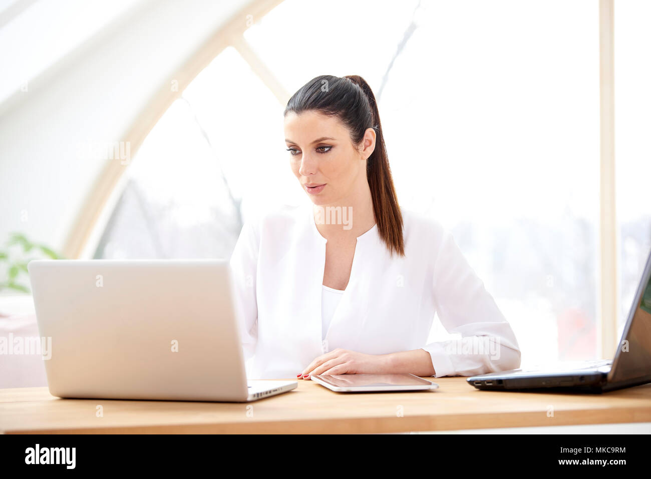 Ritratto di giovane attraente assistente vendite imprenditrice utilizzando computer portatile presso l'ufficio. Foto Stock