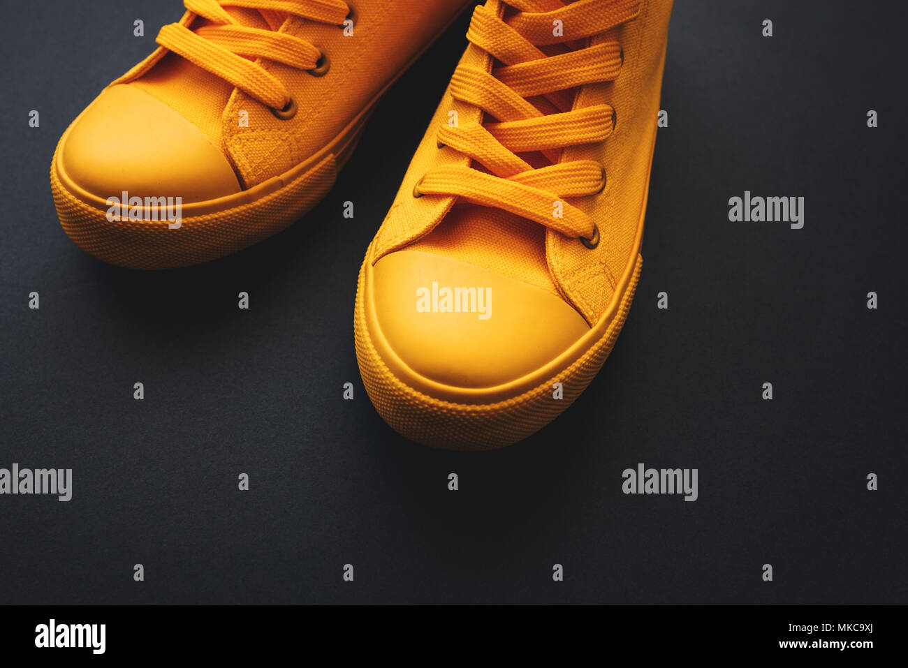 Elegante sneakers giallo su sfondo scuro con spazio di copia Foto Stock