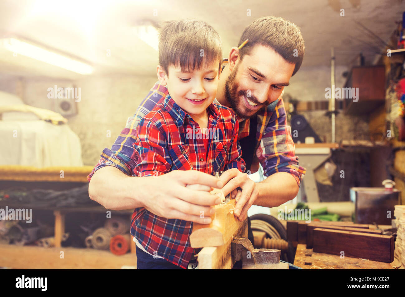 Padre e Figlio con piano in legno di rasatura in officina Foto Stock