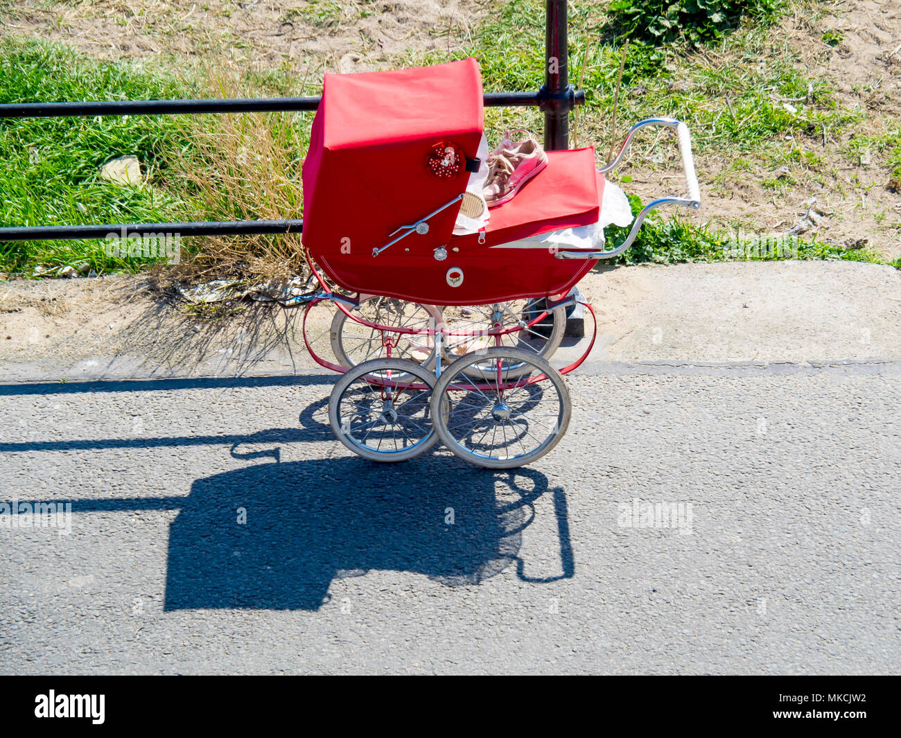 In vecchio stile anni sessanta pram stile luminoso rosso parcheggiato al mare. Foto Stock
