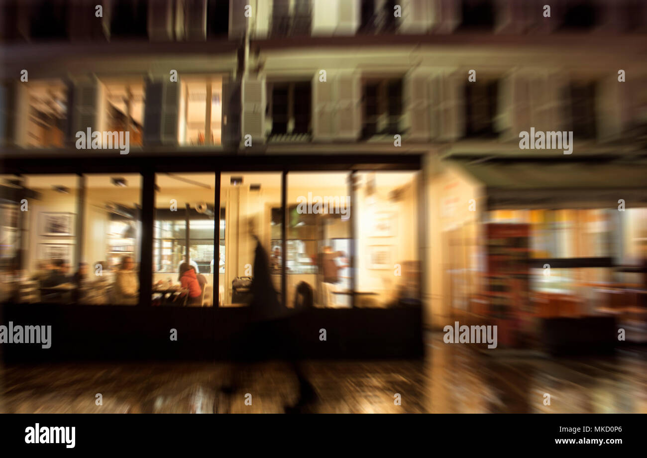 Movimento sfocato immagine dell uomo a camminare di fronte ad un ristorante di notte a Parigi. Foto Stock