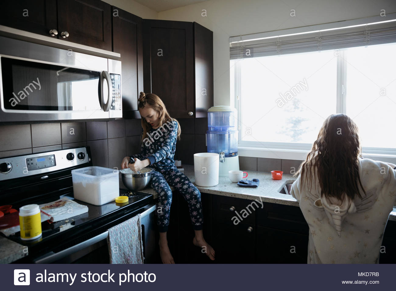 Sorelle in pigiama cottura in cucina Foto Stock