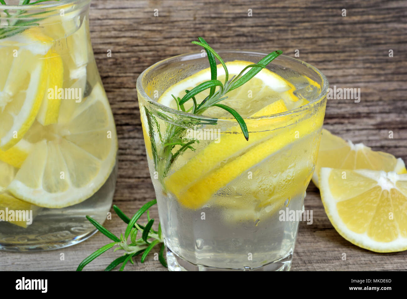 Close up di limone detox acqua con rosmarino in bicchieri sulla tavola di legno Foto Stock