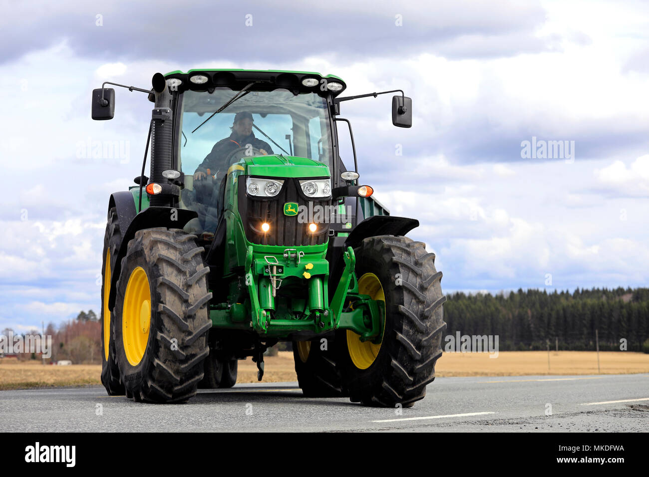 Agricoltore fa girare a destra con John Deere 6150R il trattore e rimorchio agricolo principale off road. Jokioinen, Finlandia - 30 aprile 2018. Foto Stock