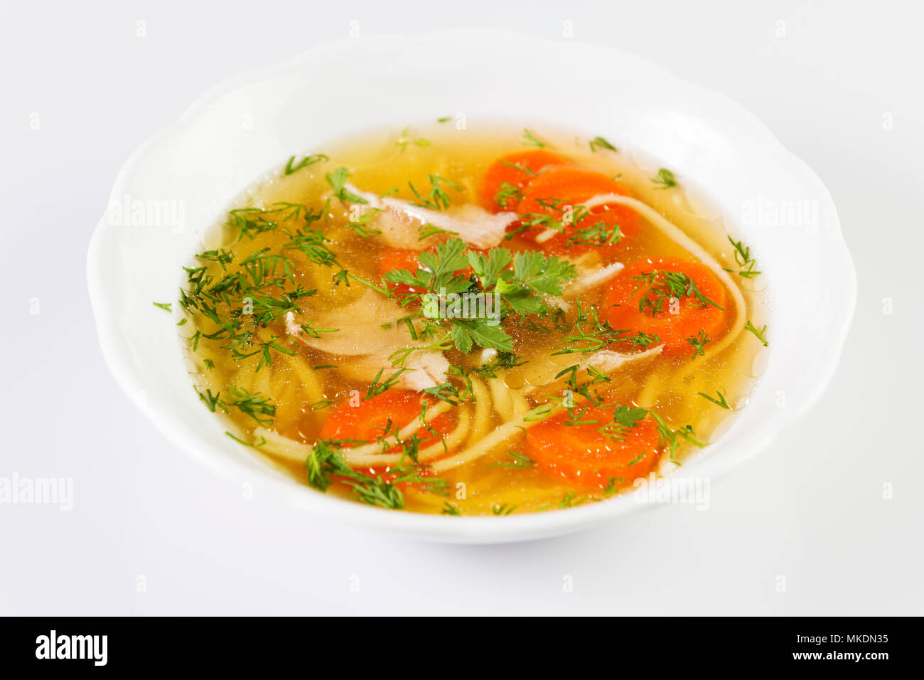 Zuppa di pollo o brodo con noodels, carne di pollo pezzi , fette di carota e le erbe in bianco ciotola. Foto Stock