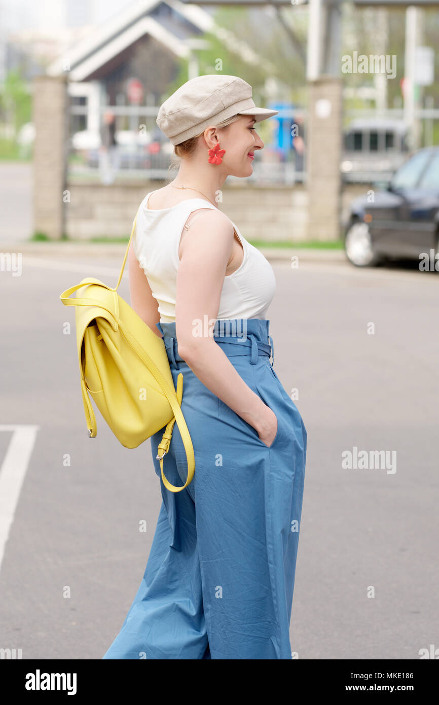 Ragazza in piazza hat, white t shrt e blu pantaloni larghi a piedi a parcheggio auto Foto Stock