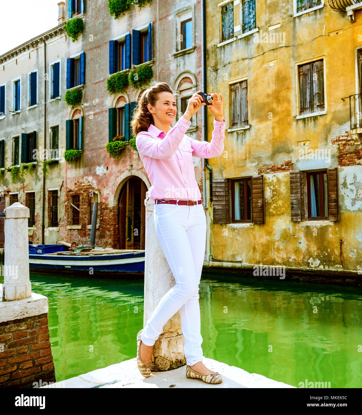 Felice giovane donna prendendo foto a venezia, Italia Foto Stock