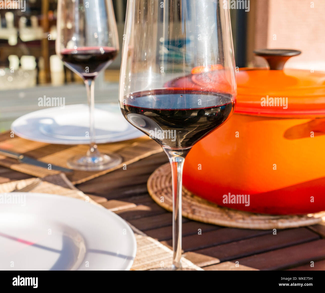 Tavolo esterno impostato con vino rosso in bicchieri e arancio Le Creuset casseruola pentola di sunny sera, Scotland, Regno Unito Foto Stock