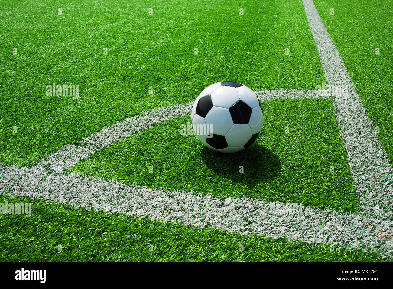 Pallone da calcio classico bianco e nero su verde erba artificiale dal punto ad angolo Foto Stock