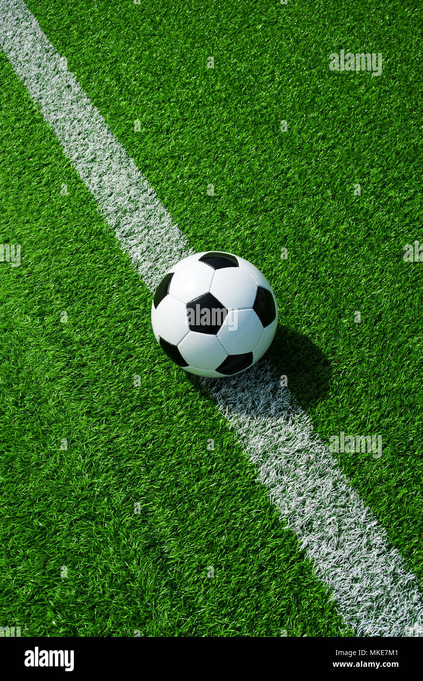 Pallone da calcio classico bianco e nero con la linea verde erba artificiale Foto Stock