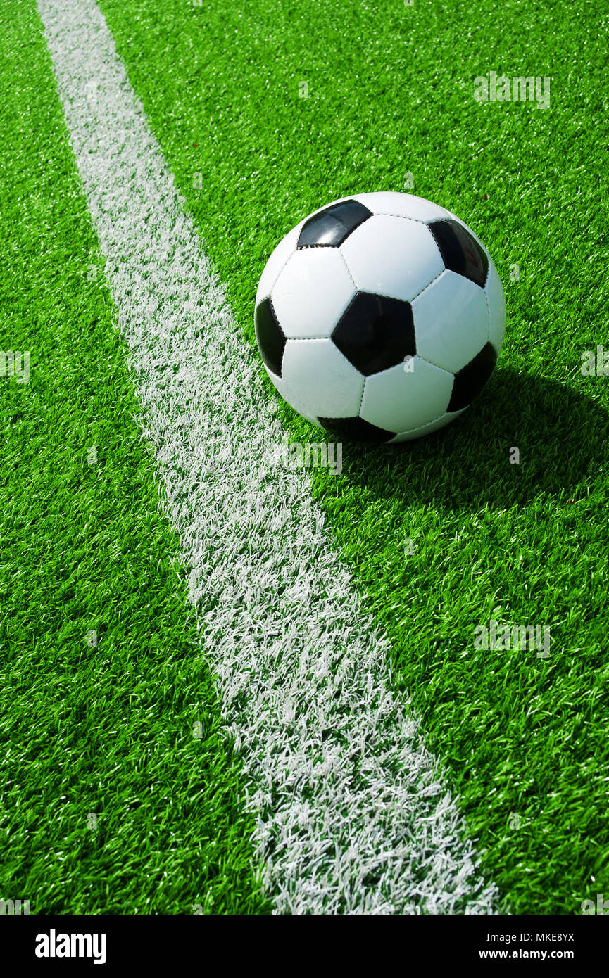 Pallone da calcio classico bianco e nero con la linea verde erba artificiale Foto Stock