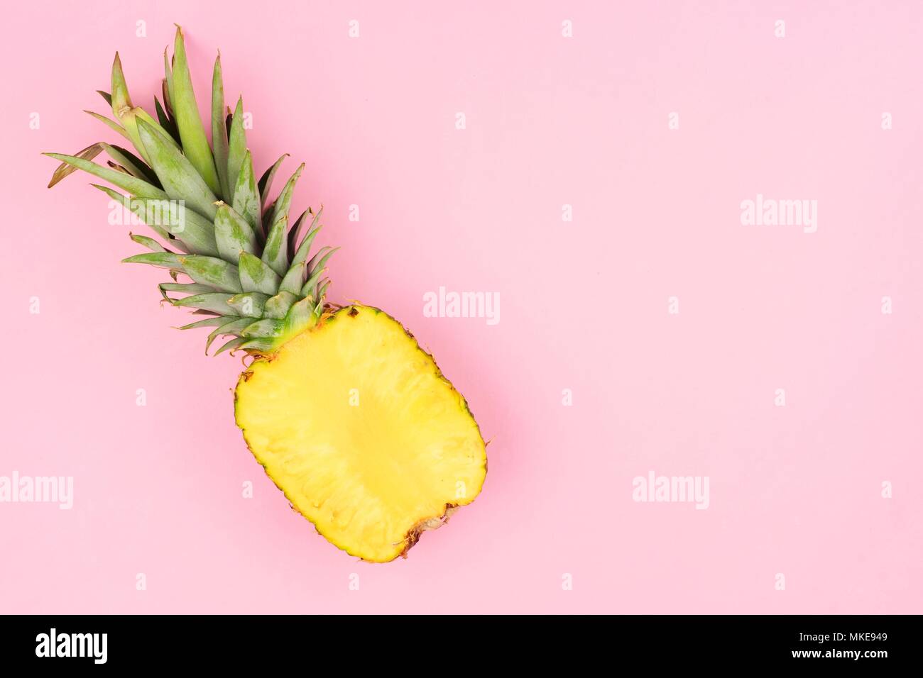Mezzo taglio succoso ananas su un pastello sfondo rosa. La minima nozione d'estate. Foto Stock