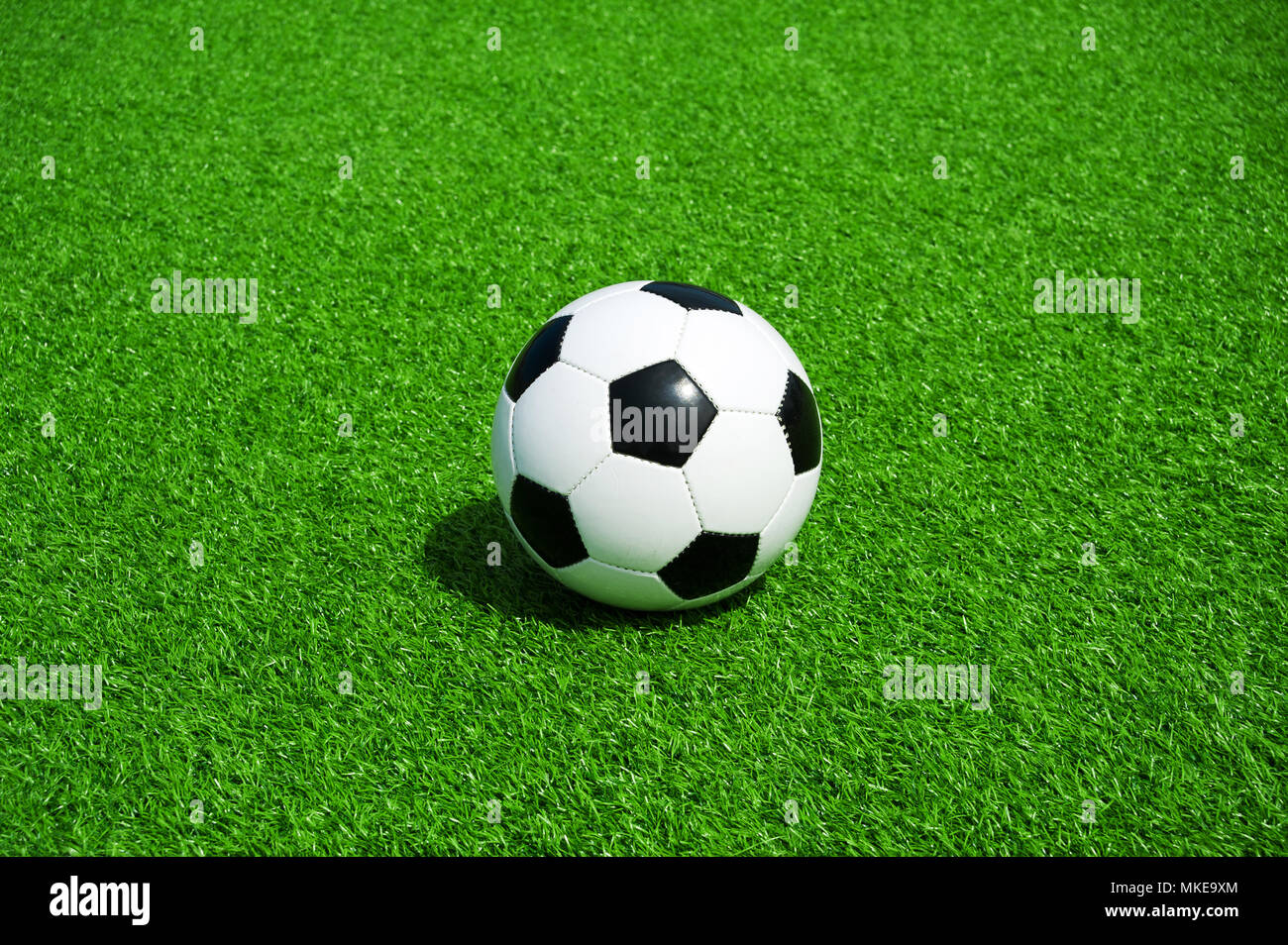 Pallone da calcio classico bianco e nero su verde erba artificiale, da soli Foto Stock