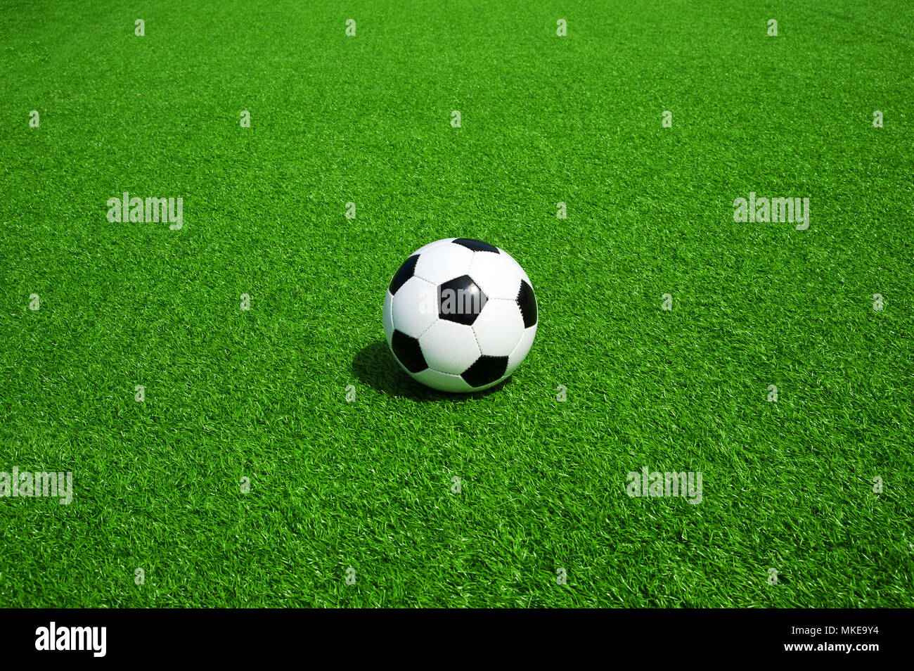 Pallone da calcio classico bianco e nero su verde erba artificiale, da soli, calcio con molto spazio per testo e grafica attorno ad un banner o un invito Foto Stock