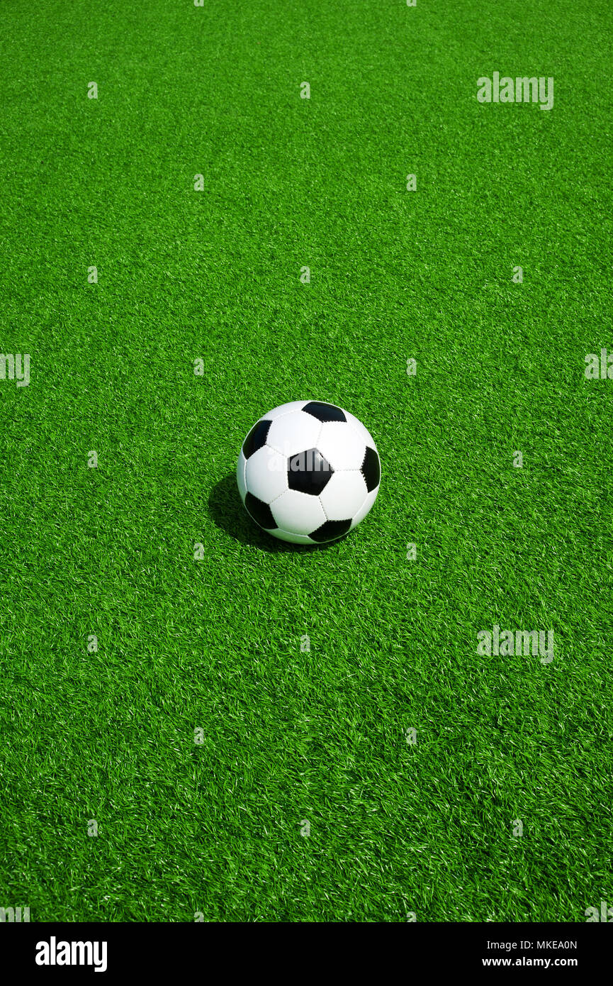 Pallone da calcio classico bianco e nero su verde erba artificiale, da soli Foto Stock