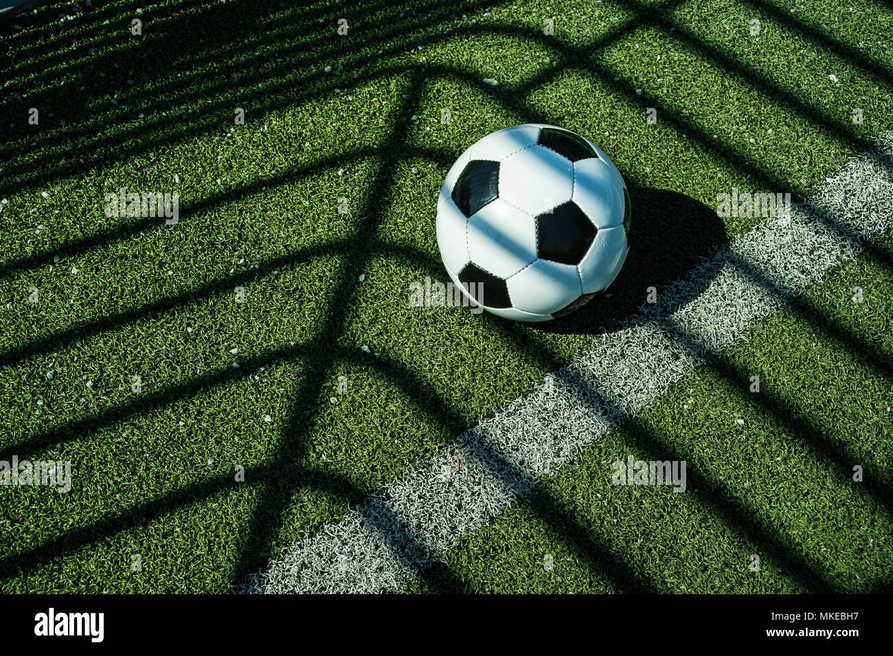 Pallone da calcio classico bianco e nero con le ombre sul terreno di un calcio artificiale obiettivo Foto Stock
