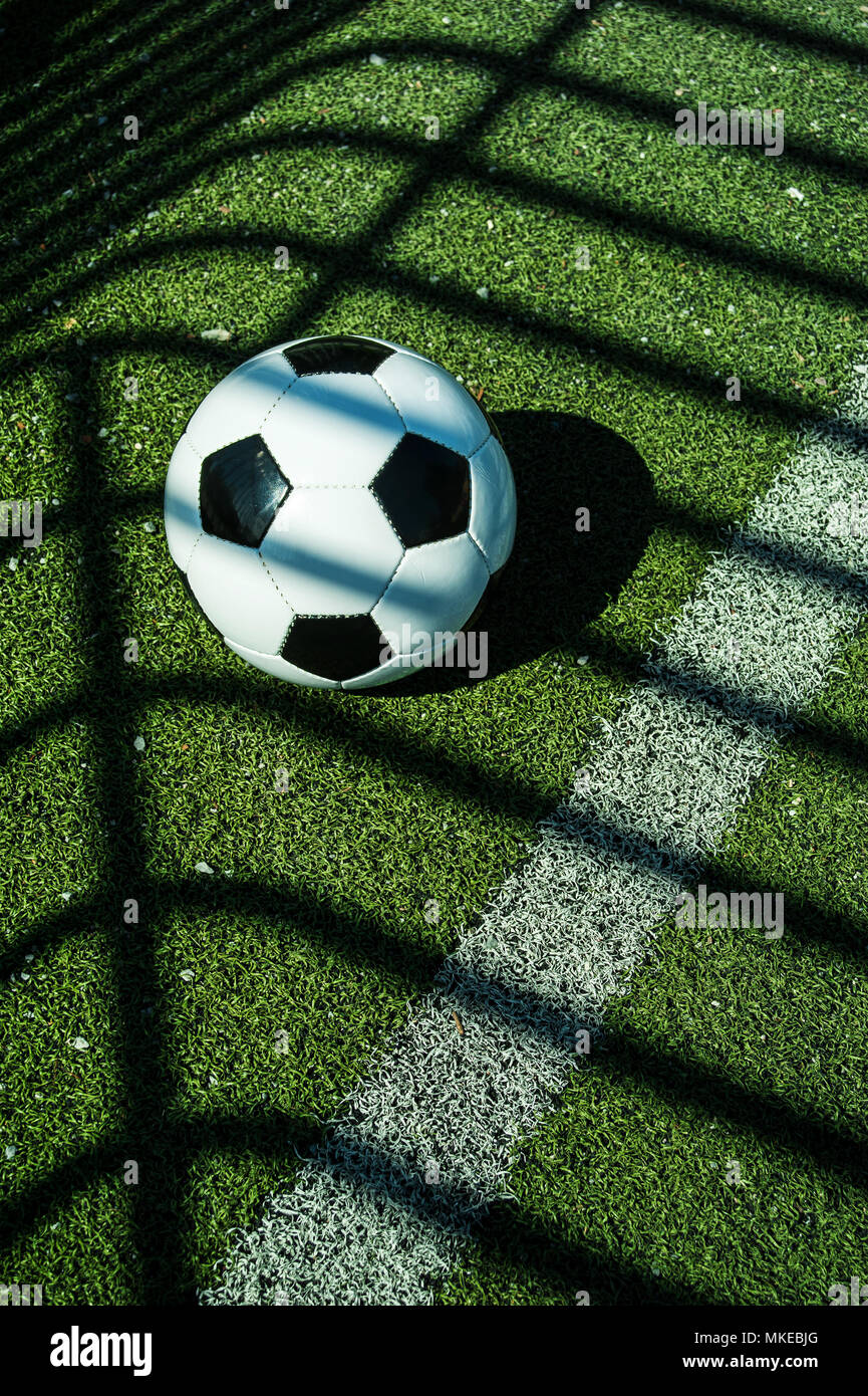 Pallone da calcio classico bianco e nero con le ombre sul terreno di un calcio artificiale obiettivo Foto Stock
