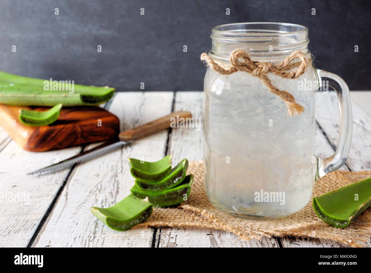 Una sana Aloe vera succo in un mason vasetto in vetro. Still Life, vista laterale in legno bianco. Foto Stock