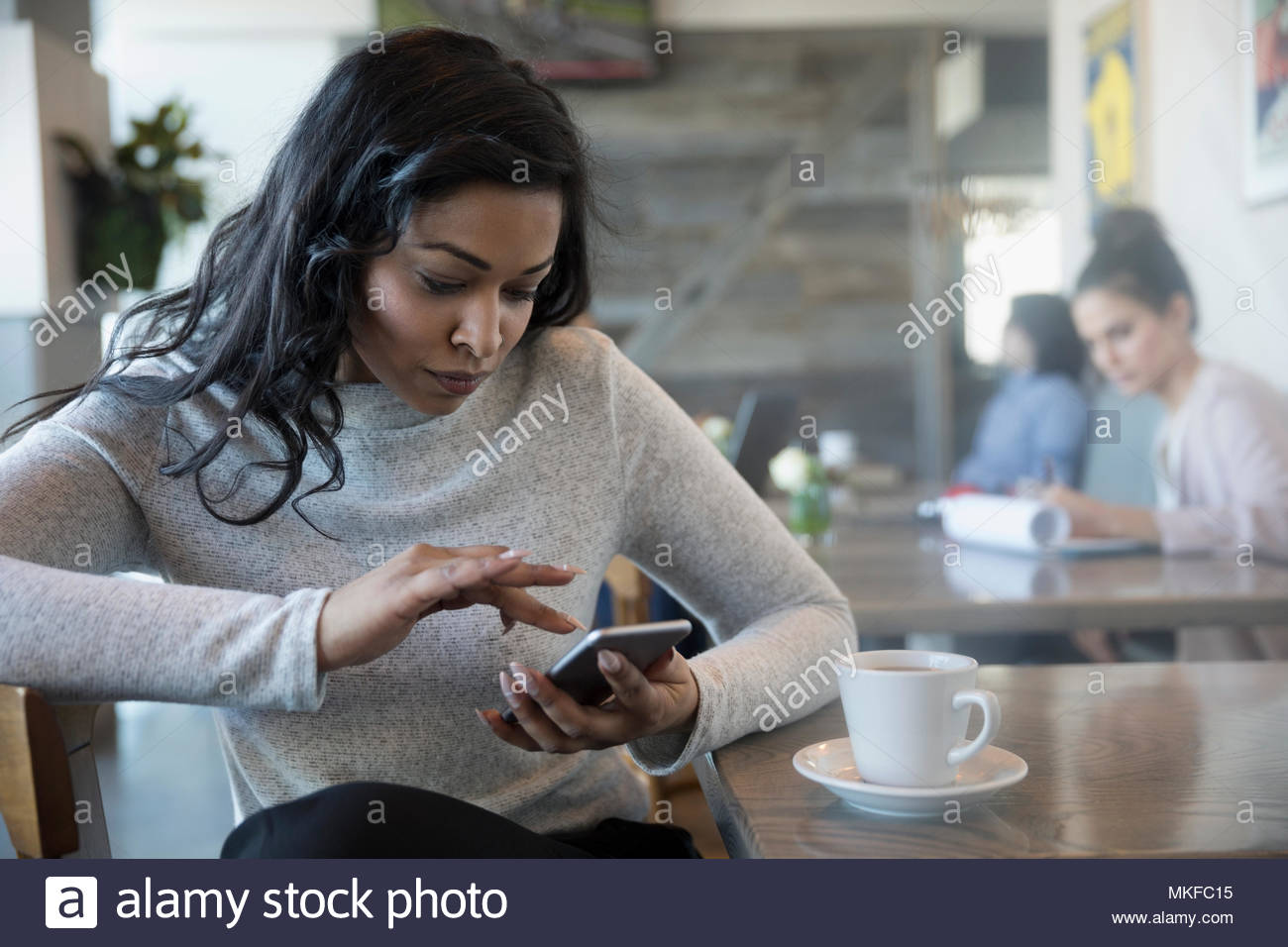 Donna che utilizza smart phone, bere il caffè nella caffetteria Foto Stock