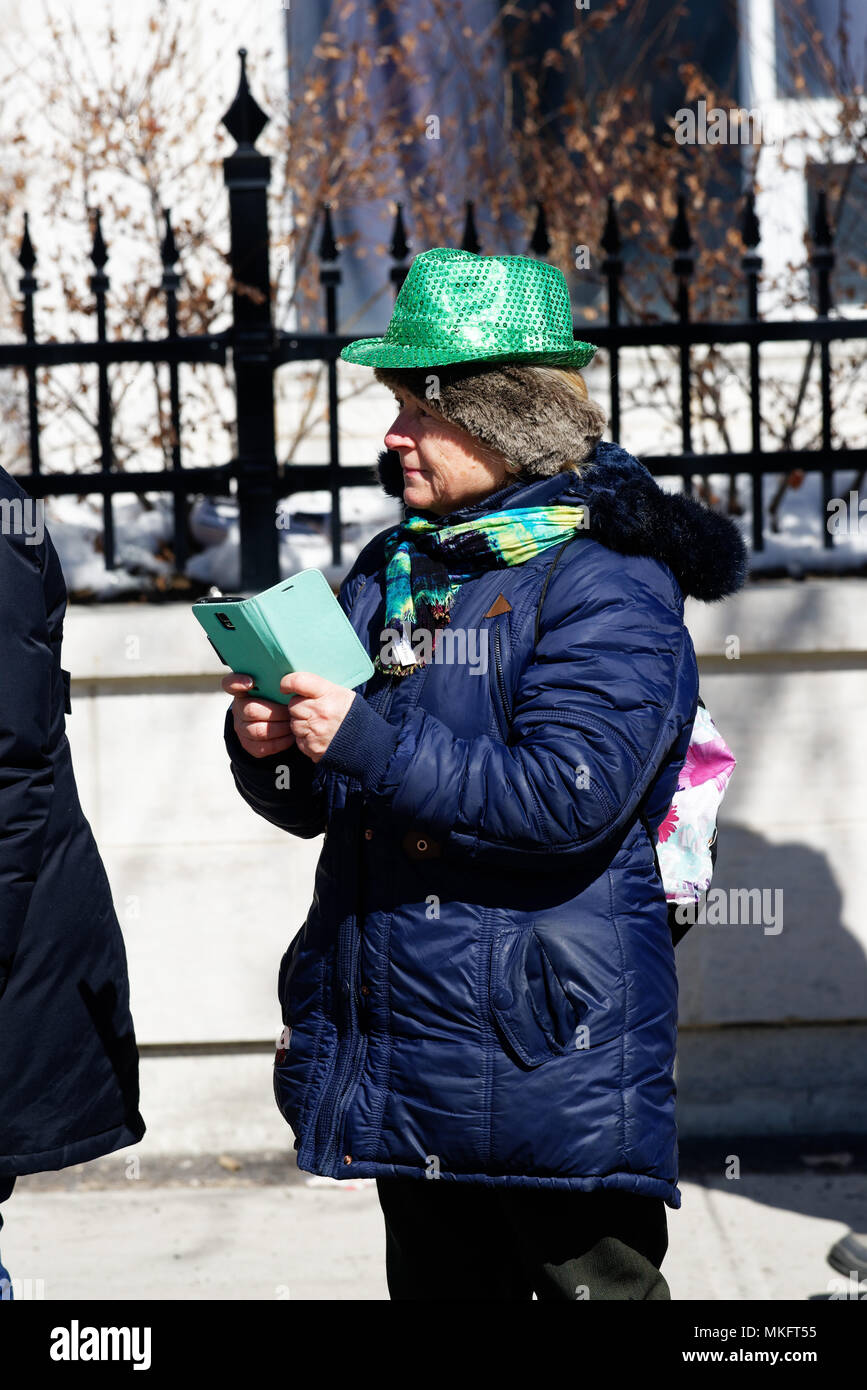 Una vecchia donna che indossa un cappello verde utilizzando il suo telefono cellulare in Montreal il giorno di San Patrizio parade Foto Stock